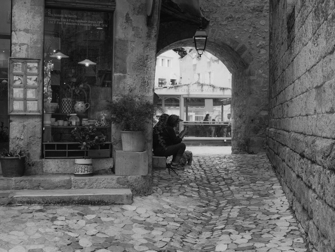 Photographer crouching on a cobblestone street taking a photo